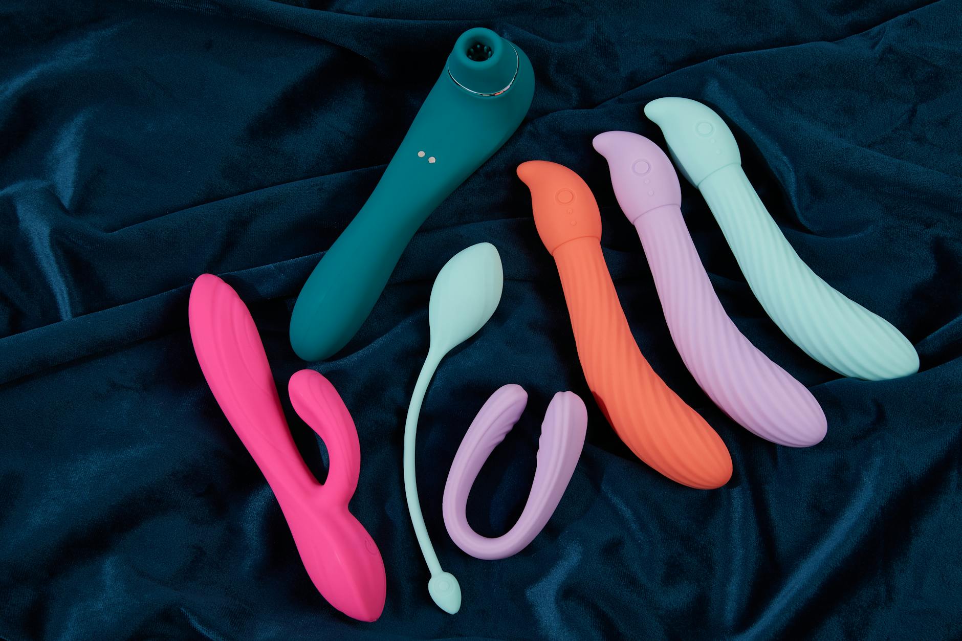 Pink vibrator on purple background with romantic candles and heart confetti