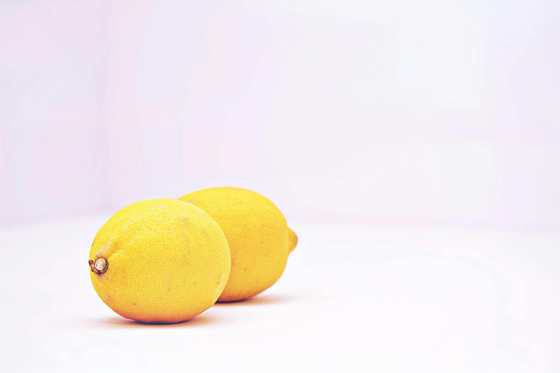 Zwei lebendige gelbe Zitronen auf minimalistischem weißem Hintergrund