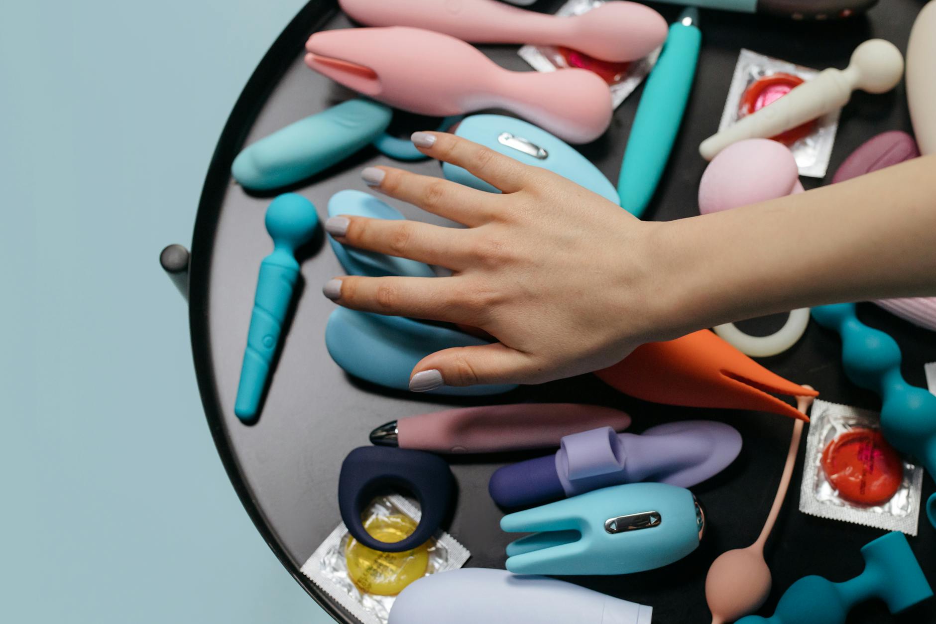 Close-up of a hand holding a sleek vibrator against a minimalistic purple backdrop