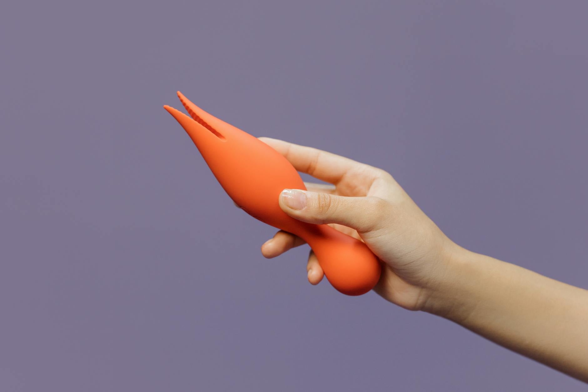 Close-up of hands holding a Lemon vibrator against a purple backdrop, showing intimate partnership