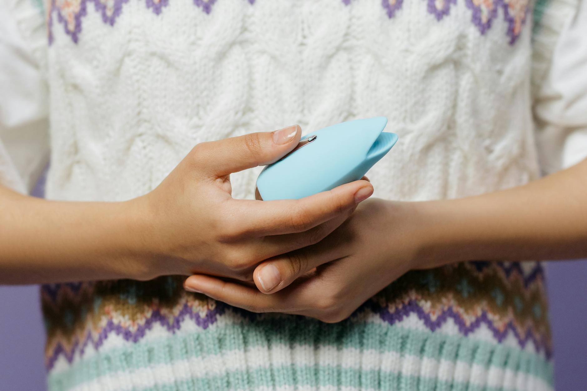 Woman holding two colorful vibrators against a purple background, representing personal exploration and partnership acceptance.