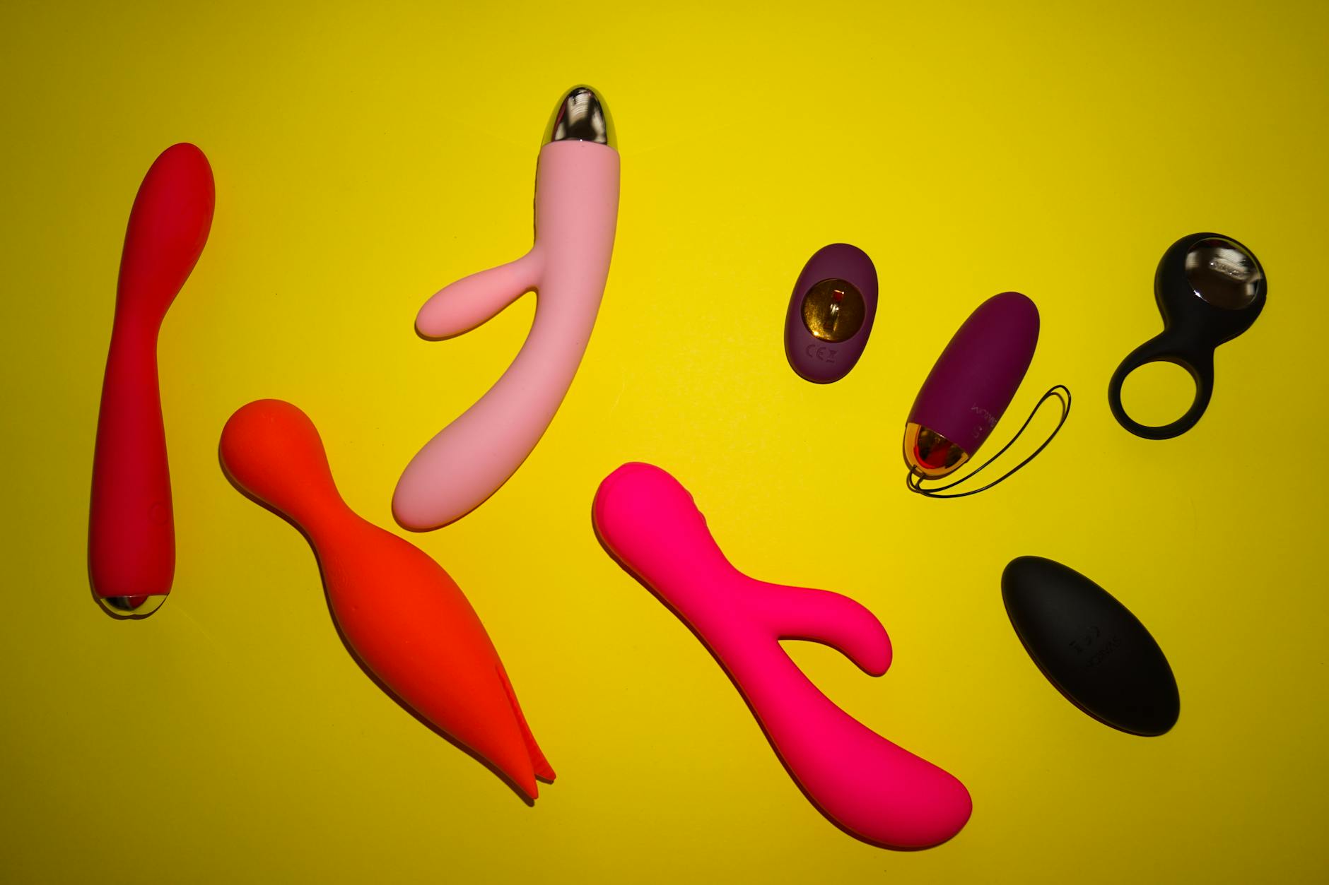 Woman holding blue and pink silicone vibrators in thoughtful consideration